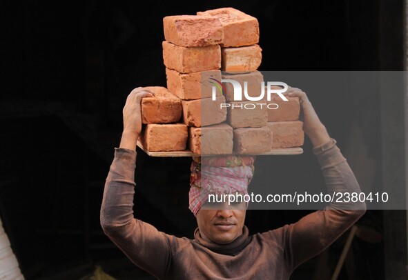 Indian Labour carries pile of bricks on his head near a construction site at Gurugram, Haryana on 16th December 2017. 