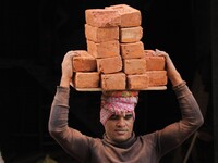 Indian Labour carries pile of bricks on his head near a construction site at Gurugram, Haryana on 16th December 2017. (