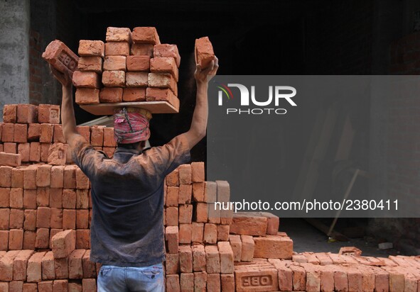 Indian Labour carries pile of bricks on his head near a construction site at Gurugram, Haryana on 16th December 2017. 