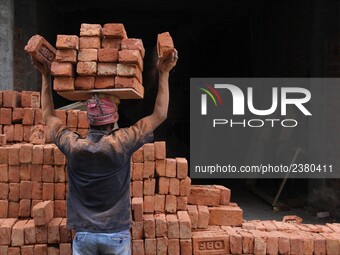 Indian Labour carries pile of bricks on his head near a construction site at Gurugram, Haryana on 16th December 2017. (