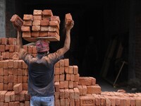 Indian Labour carries pile of bricks on his head near a construction site at Gurugram, Haryana on 16th December 2017. (