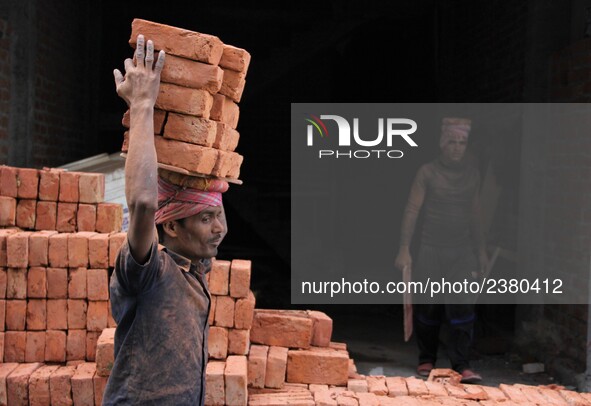 Indian Labour carries pile of bricks on his head near a construction site at Gurugram, Haryana on 16th December 2017. 