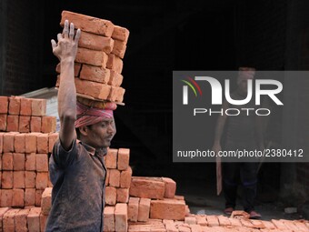 Indian Labour carries pile of bricks on his head near a construction site at Gurugram, Haryana on 16th December 2017. (