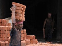 Indian Labour carries pile of bricks on his head near a construction site at Gurugram, Haryana on 16th December 2017. (