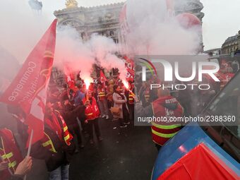 French General Confederation of Labour (CGT) unionists hold smoke canisters as they gather in front of Paris' Opera Garnier on December 20,...