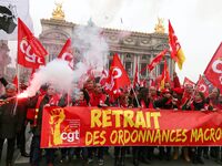 People hold a banner reading "withdrawal of Macron's executive orders" during a demonstration called by French General Confederation of Labo...