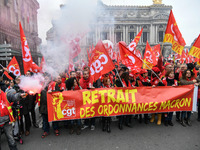 People hold a banner reading "withdrawal of Macron's executive orders" during a demonstration called by French General Confederation of Labo...