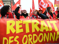 People hold a banner reading "withdrawal of Macron's executive orders" during a demonstration called by French General Confederation of Labo...