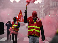 French General Confederation of Labour (CGT) unionists hold smoke canisters as they gather in front of Paris' Opera Garnier on December 20,...