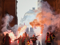 French General Confederation of Labour (CGT) unionists hold smoke canisters as they gather in front of Paris' Opera Garnier on December 20,...