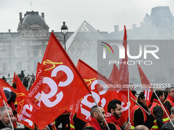 French General Confederation of Labour (CGT) unionists hold smoke canisters as they gather in front of Paris' Louvre Museum on December 20,...