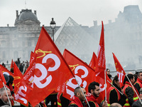 French General Confederation of Labour (CGT) unionists hold smoke canisters as they gather in front of Paris' Louvre Museum on December 20,...