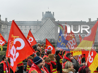 French General Confederation of Labour (CGT) unionists hold smoke canisters as they gather in front of Paris' Louvre Museum on December 20,...