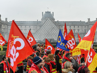 French General Confederation of Labour (CGT) unionists hold smoke canisters as they gather in front of Paris' Louvre Museum on December 20,...