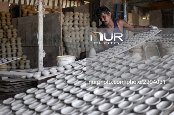 A pottery maker arranging a clay lantern or ‘diya’ in Kuala Selangor, Malaysia. Diyas are the small earthen lamps primarily used during Diwa...