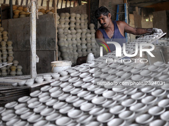 A pottery maker arranging a clay lantern or ‘diya’ in Kuala Selangor, Malaysia. Diyas are the small earthen lamps primarily used during Diwa...