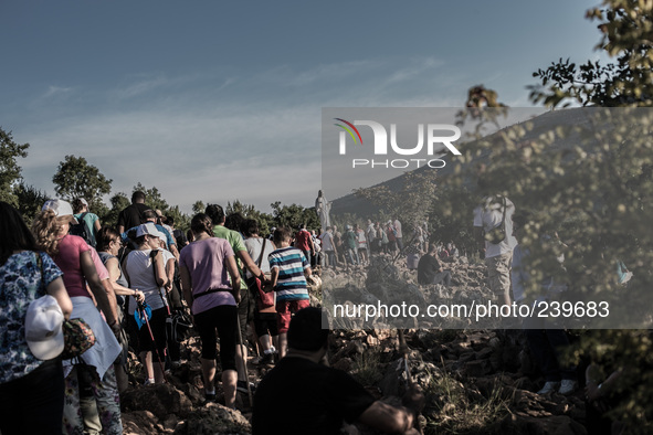 A statue of Virgin Mary on the the Apparition Hill, in Medjugorie. Pilgrims on a steep path that leads on the very place of the apparitions...