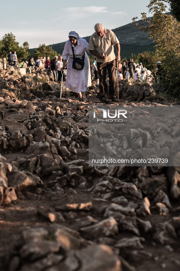 A man help a nun on a steep path that leads on the very place of the apparitions of Our Lady,  called Podbrdo and Apparition Hill.Almost one...