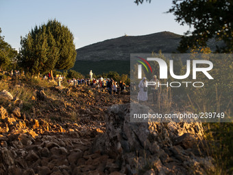 A man help a nun on a steep path that leads on the very place of the apparitions of Our Lady,  called Podbrdo and Apparition Hill.Almost one...