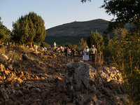 A man help a nun on a steep path that leads on the very place of the apparitions of Our Lady,  called Podbrdo and Apparition Hill.Almost one...