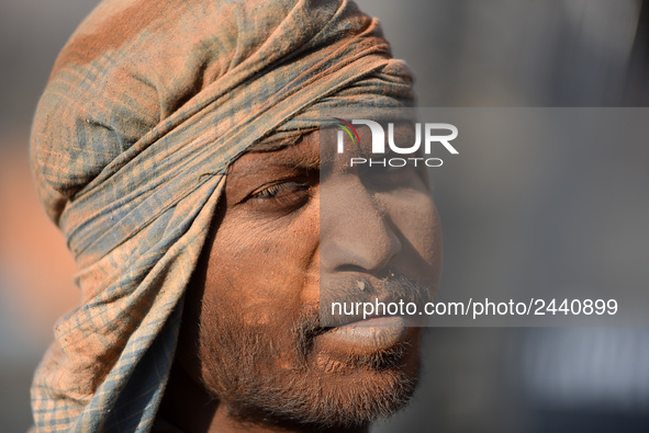 A layer of dust seen on Portrait on Indian labourers as after stacks bricks by balancing them onto his head at a brick factory in Lalitpur,...