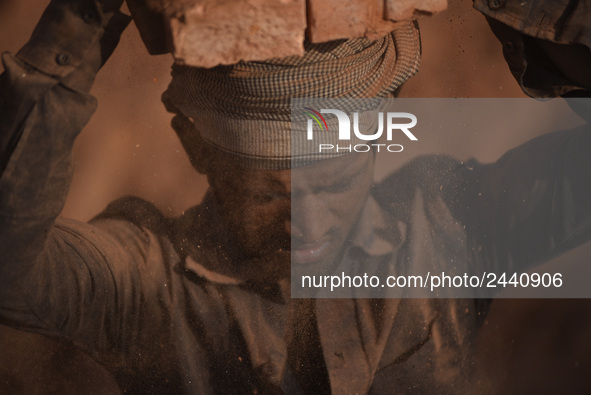 A Migrant Indian labourer stacks bricks by balancing them onto his head at a brick factory in Lalitpur, Nepal on Tuesday, January 23, 2018....