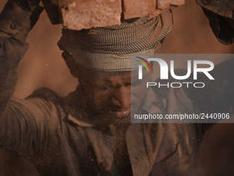 A Migrant Indian labourer stacks bricks by balancing them onto his head at a brick factory in Lalitpur, Nepal on Tuesday, January 23, 2018....