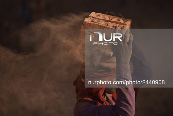 A Migrant Indian labourer stacks bricks by balancing them onto his head at a brick factory in Lalitpur, Nepal on Tuesday, January 23, 2018....