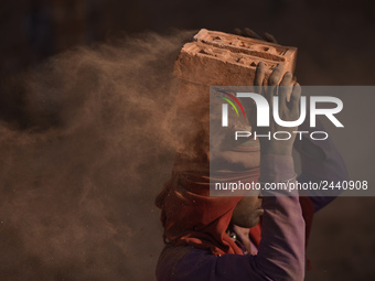 A Migrant Indian labourer stacks bricks by balancing them onto his head at a brick factory in Lalitpur, Nepal on Tuesday, January 23, 2018....