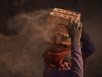 A Migrant Indian labourer stacks bricks by balancing them onto his head at a brick factory in Lalitpur, Nepal on Tuesday, January 23, 2018....