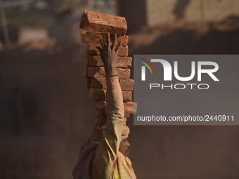 A Migrant Indian labourer stacks bricks by balancing them onto his head at a brick factory in Lalitpur, Nepal on Tuesday, January 23, 2018....