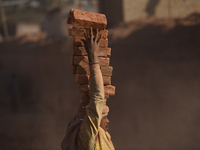 A Migrant Indian labourer stacks bricks by balancing them onto his head at a brick factory in Lalitpur, Nepal on Tuesday, January 23, 2018....