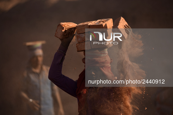 A Migrant Indian labourer stacks bricks by balancing them onto his head at a brick factory in Lalitpur, Nepal on Tuesday, January 23, 2018....