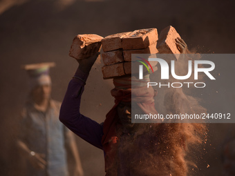 A Migrant Indian labourer stacks bricks by balancing them onto his head at a brick factory in Lalitpur, Nepal on Tuesday, January 23, 2018....