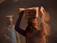 A Migrant Indian labourer stacks bricks by balancing them onto his head at a brick factory in Lalitpur, Nepal on Tuesday, January 23, 2018....