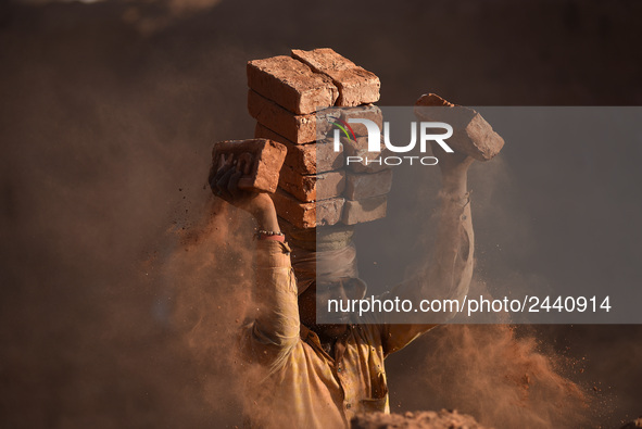 A Migrant Indian labourer stacks bricks by balancing them onto his head at a brick factory in Lalitpur, Nepal on Tuesday, January 23, 2018....