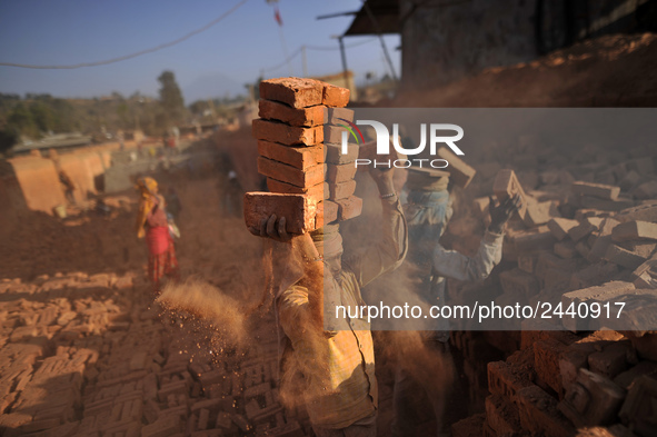 A Migrant Indian labourer stacks bricks by balancing them onto his head at a brick factory in Lalitpur, Nepal on Tuesday, January 23, 2018....