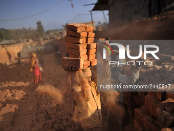 A Migrant Indian labourer stacks bricks by balancing them onto his head at a brick factory in Lalitpur, Nepal on Tuesday, January 23, 2018....