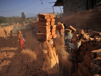 A Migrant Indian labourer stacks bricks by balancing them onto his head at a brick factory in Lalitpur, Nepal on Tuesday, January 23, 2018....