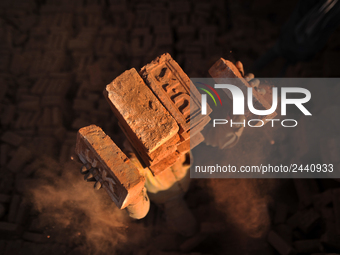 A Migrant Indian labourer stacks bricks by balancing them onto his head at a brick factory in Lalitpur, Nepal on Tuesday, January 23, 2018....