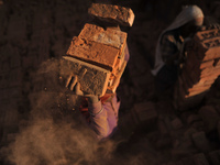 A Migrant Indian labourer stacks bricks by balancing them onto his head at a brick factory in Lalitpur, Nepal on Tuesday, January 23, 2018....