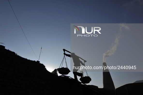 A Migrant worker from India, carries mixed soil at a brick factory in Lalitpur, Nepal on Tuesday, January 23, 2018. 