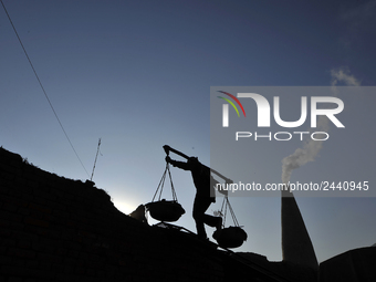 A Migrant worker from India, carries mixed soil at a brick factory in Lalitpur, Nepal on Tuesday, January 23, 2018. (