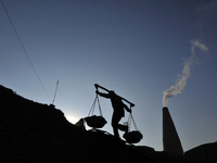 A Migrant worker from India, carries mixed soil at a brick factory in Lalitpur, Nepal on Tuesday, January 23, 2018. (