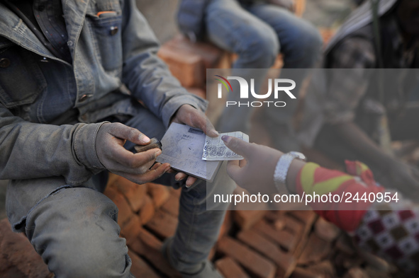 A worker puts stamp as a Migrant Indian labourer carry stacks bricks at a brick factory in Lalitpur, Nepal on Tuesday, January 23, 2018. Ind...