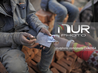 A worker puts stamp as a Migrant Indian labourer carry stacks bricks at a brick factory in Lalitpur, Nepal on Tuesday, January 23, 2018. Ind...