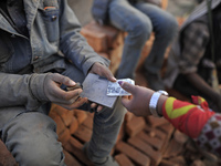 A worker puts stamp as a Migrant Indian labourer carry stacks bricks at a brick factory in Lalitpur, Nepal on Tuesday, January 23, 2018. Ind...