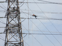 Workers assemble cables in high-voltage power towers without adequate safety equipment, even among them seen wearing only shorts and not wea...