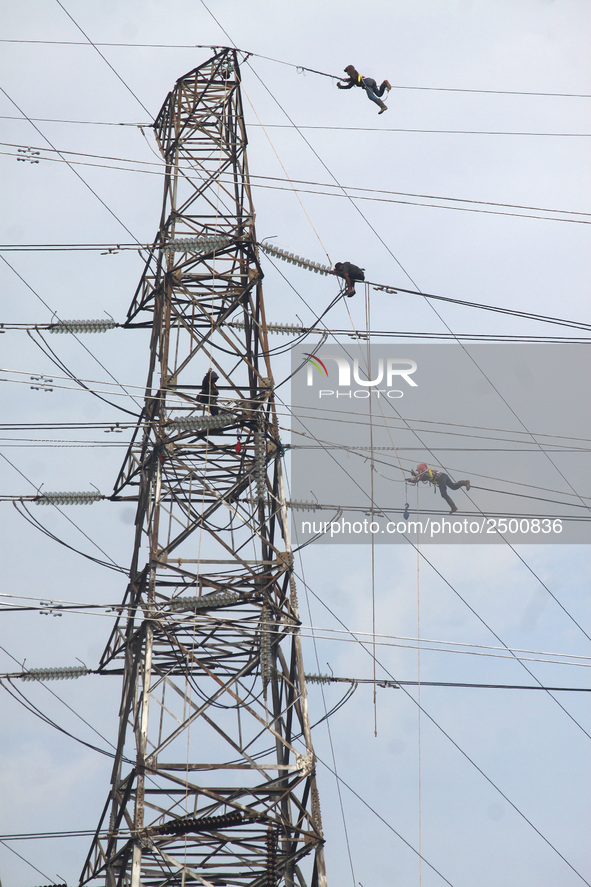 Workers assemble cables in high-voltage power towers without adequate safety equipment, even among them seen wearing only shorts and not wea...