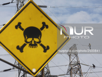 Workers assemble cables in high-voltage power towers without adequate safety equipment, even among them seen wearing only shorts and not wea...